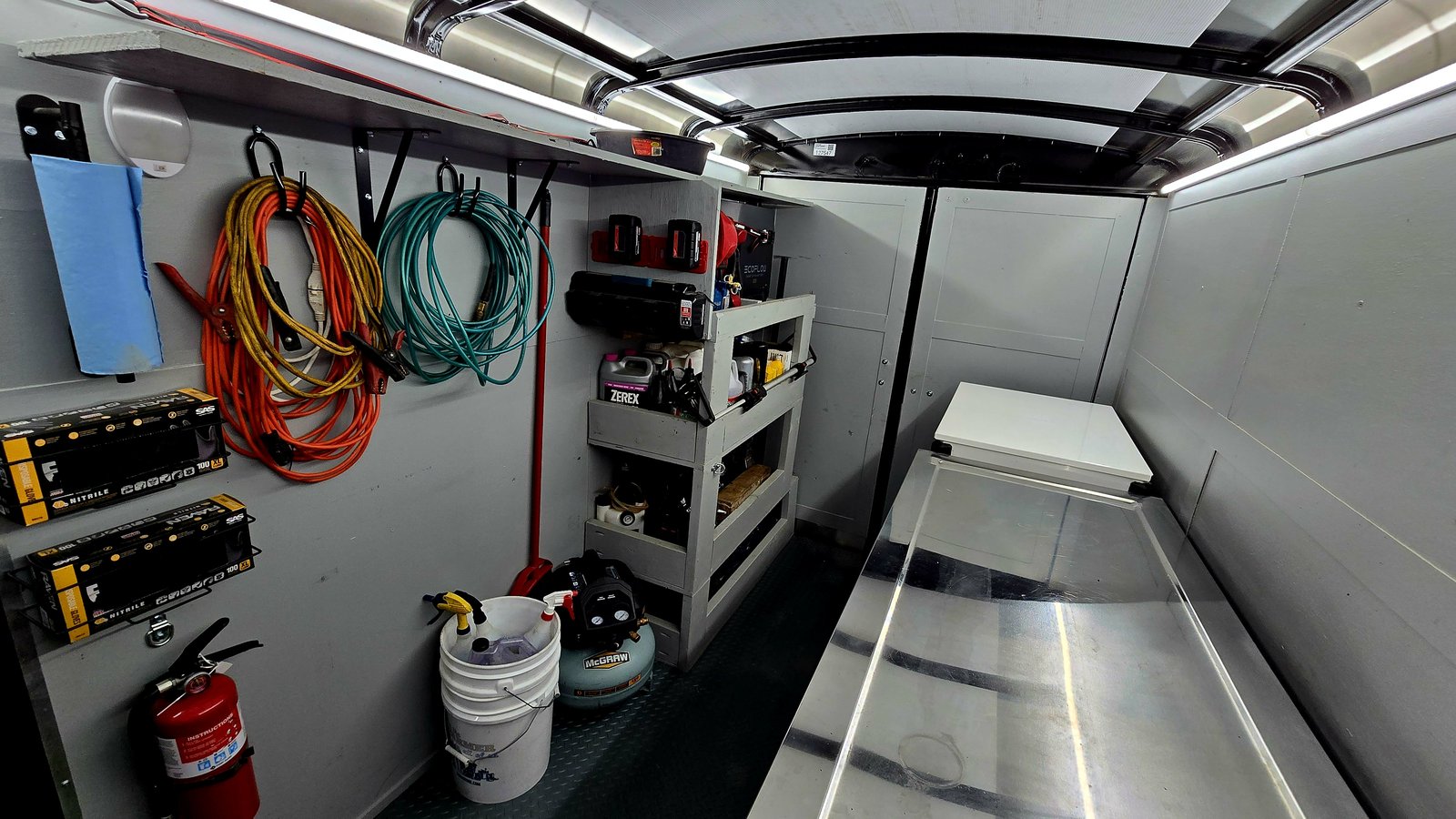 Inside the Next Gen Auto Repair mobile shop trailer — full-size tool chests, mounted spare, and fluid shelving